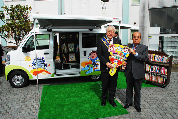 たびりん号の前で、横田会長（左）と石井市長